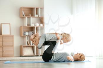 Mother with little girl doing yoga at home�