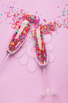 Glasses with confetti on color background�