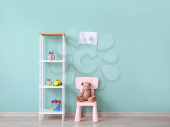 Stylish furniture with toys near color wall in children's room�