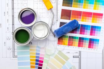 Cans of paint with roller, palette samples and house plan�