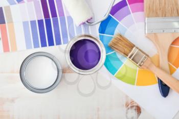 Cans of paint with supplies and palette samples on light background�