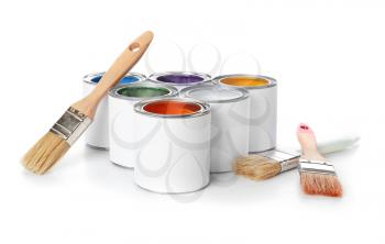 Cans of paints with brushes on color background�