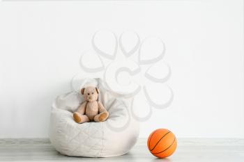 Beanbag chair with teddy bear and ball near light wall in children's room�