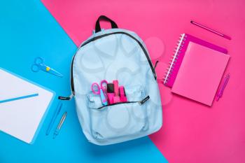 School backpack with stationery on color background�