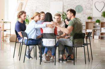 People calming woman at group therapy session�