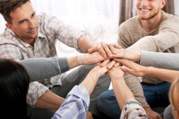 People putting hands together at group therapy session�