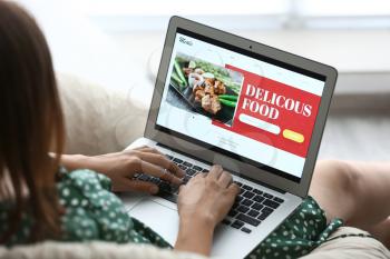 Young woman using laptop for ordering food at home�