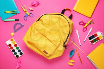 School backpack and stationery on color background�