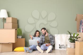 Young couple with cardboard boxes and laptop after moving into new house�