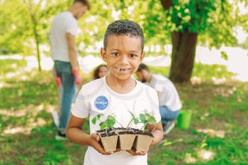 Little African-American volunteer with young plants outdoors�