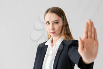 Young businesswoman showing STOP gesture on white background�