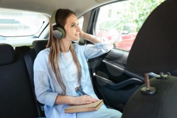 Beautiful young woman listening to audiobook in car�