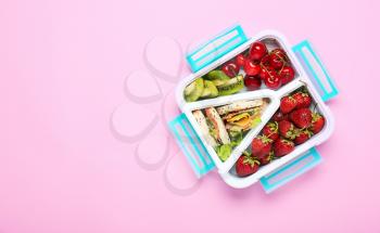 School lunch box with tasty food on color background�
