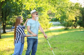 Blind mature man with daughter walking in park�