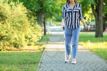 Young blind woman walking in park�