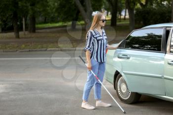 Young blind woman opening car door�