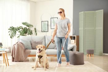 Young blind woman with guide dog at home�