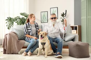 Blind mature man with daughter and guide dog at home�