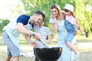 Happy family cooking tasty food on barbecue grill outdoors�