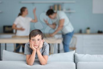 Sad little boy and his quarreling parents at home�