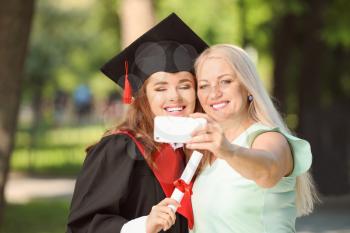 Happy young woman with her mother taking selfie on graduation day�