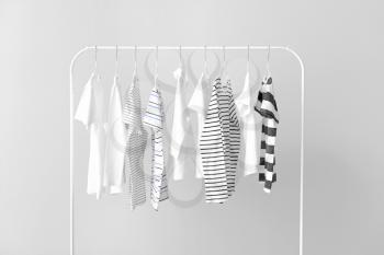 Stylish kid clothes hanging on rack against light background�