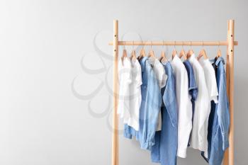 Rack with hanging clothes on light background�
