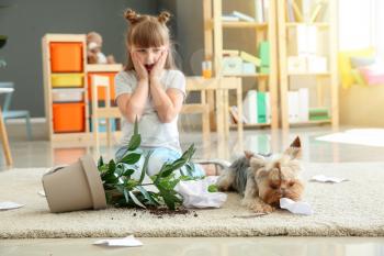 Little girl and her dog near dropped houseplant and paper pieces on carpet�