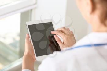 Female doctor using modern tablet computer in clinic, closeup�