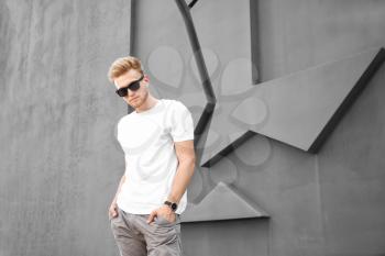 Man in stylish t-shirt near grey wall�