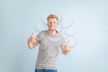 Man pointing at his t-shirt against color background�
