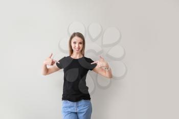 Woman pointing at her t-shirt against light background�
