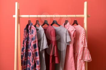 Rack with hanging clothes on color background�
