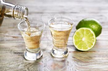 Pouring of tequila in glass on table�