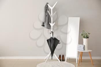 Stylish umbrella with clothes in interior of hall�