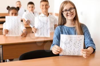 Happy girl with results of school test in classroom�