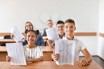 Happy classmates with results of school test in classroom�
