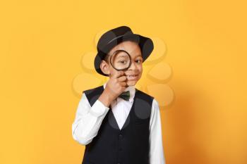 Little African-American detective with magnifier on color background�
