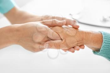 Doctor supporting elderly woman in clinic, closeup�