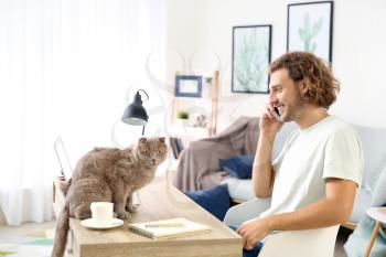 Man with cute funny cat working at home�