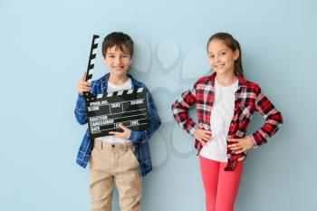 Cute little children with movie clapper on color background�