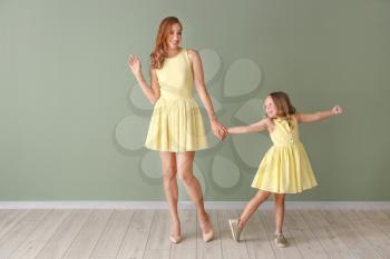 Beautiful woman and her little daughter near color wall�