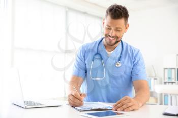 Male nurse working at table in clinic�