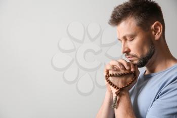 Religious man praying on light background�