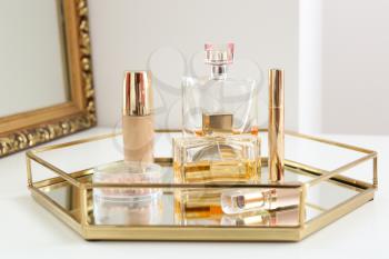 Tray with makeup cosmetics and bottles of perfumes on dressing table�