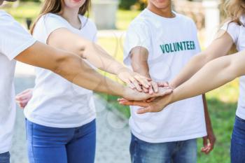 Group of volunteers putting hands together outdoors�