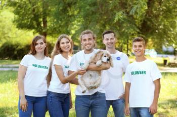 Volunteers with cute dog outdoors�