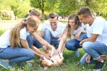 Group of volunteers with cute dog outdoors�