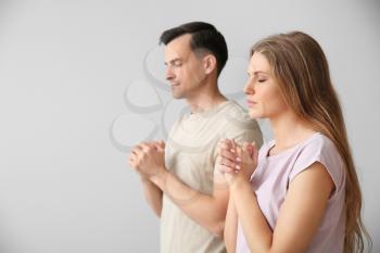 Religious couple praying to God on light background�