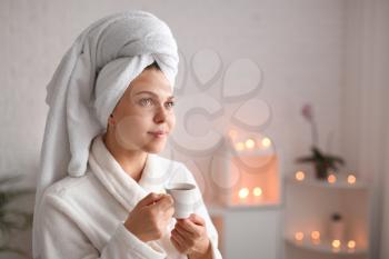 Beautiful young woman with cup of tea relaxing in spa salon�